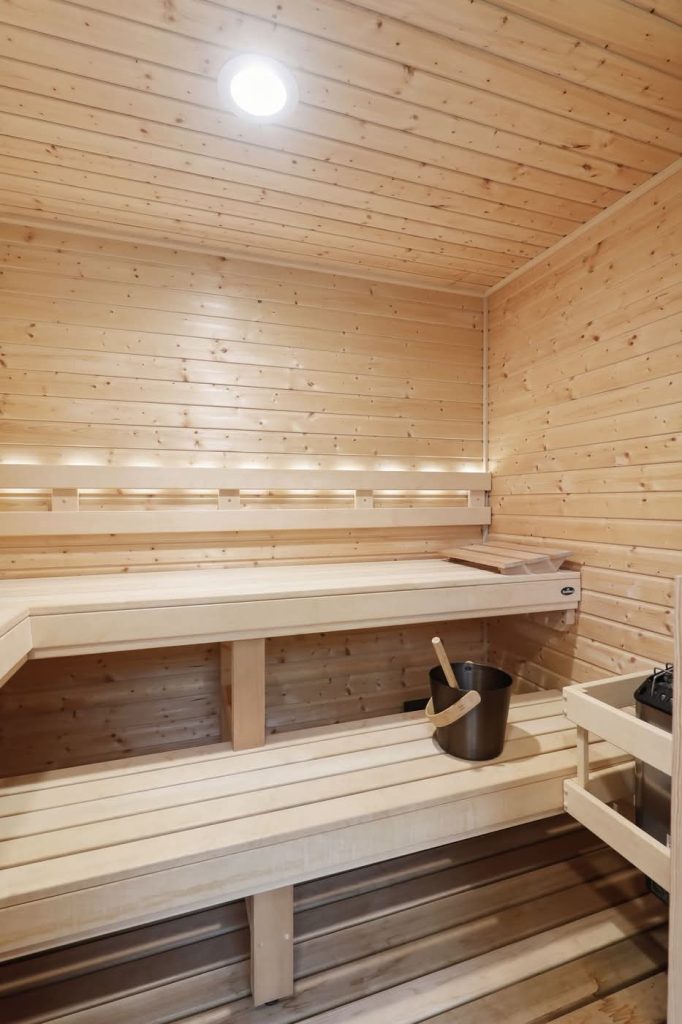 Wood-paneled sauna with benches and bucket