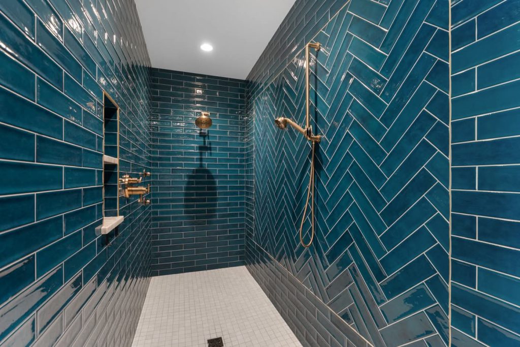 Modern shower with teal herringbone tiles and brass fixtures