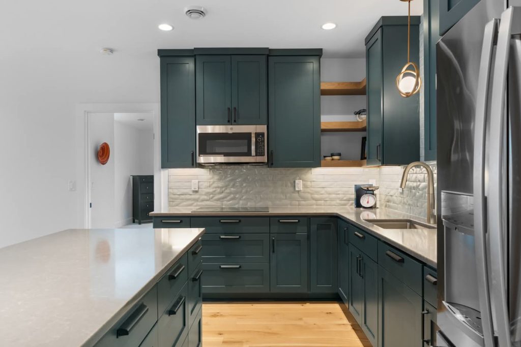Modern kitchen with dark green cabinets and white countertops