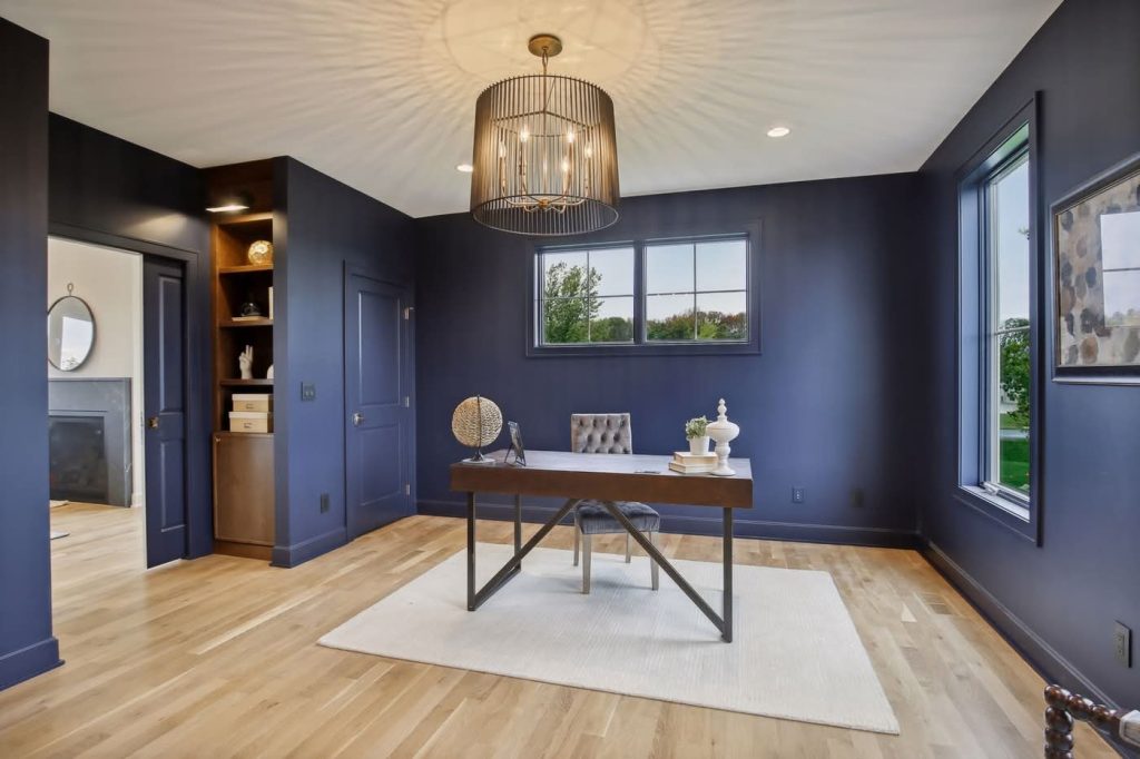 Modern navy home office with wooden desk and chandelier