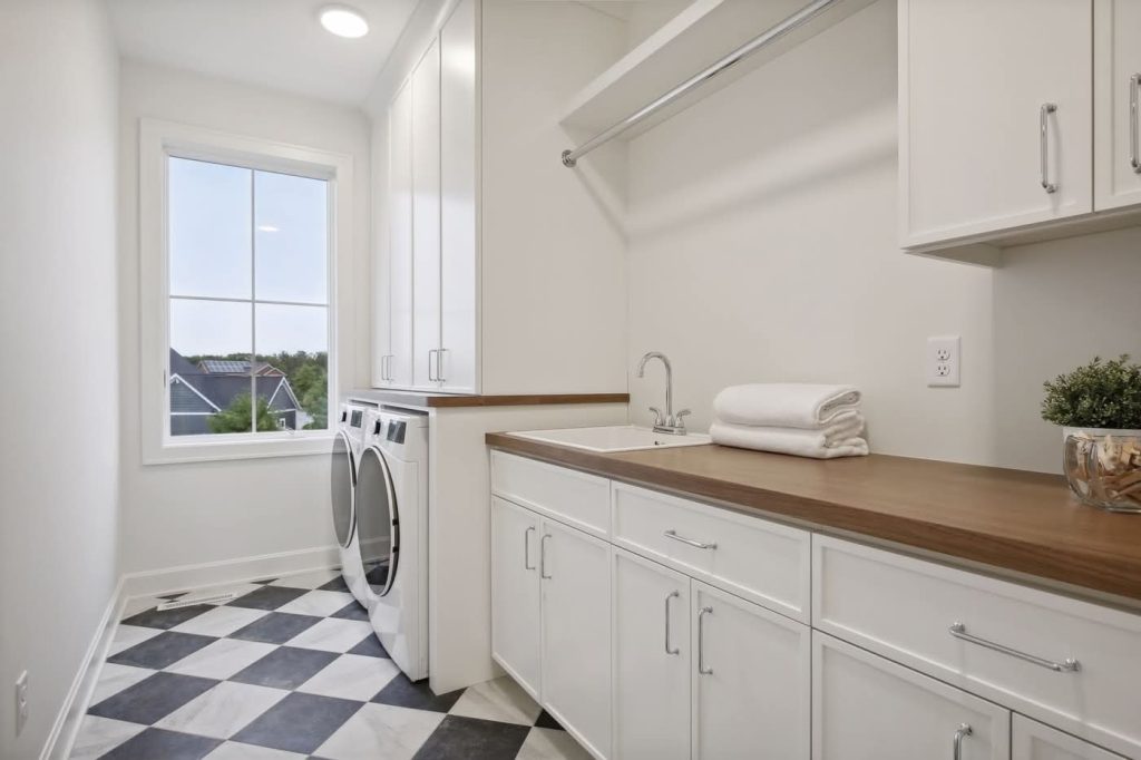 Bright laundry room with washer, sink, cabinets.