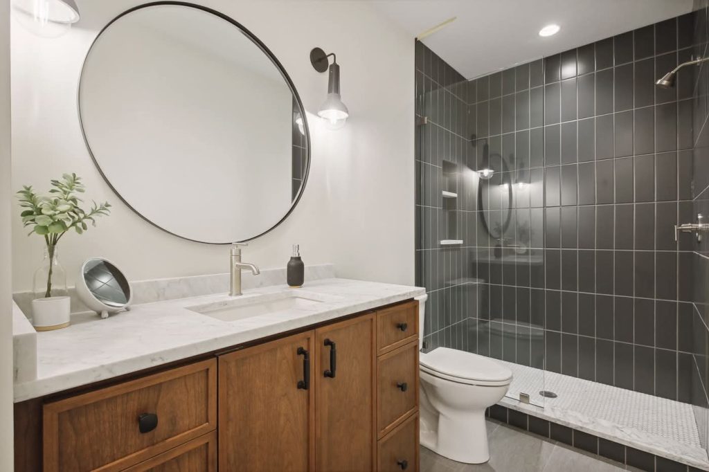 Modern bathroom with wooden vanity and black tile shower