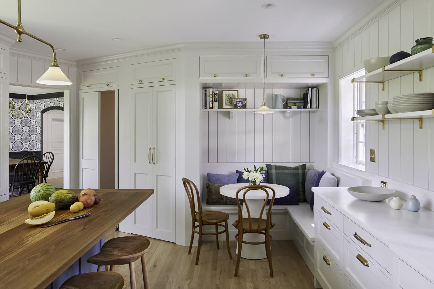 Bright white kitchen with wood island and banquette