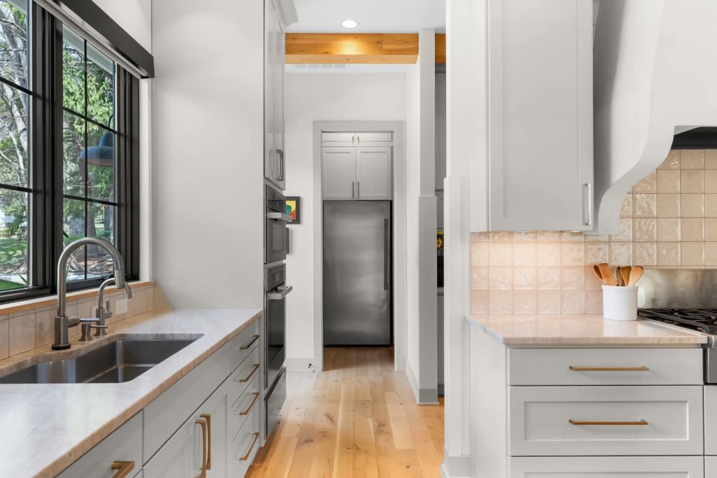 Modern white kitchen with large window and wood floors
