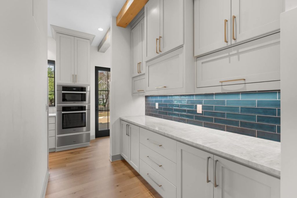 Modern kitchen pantry with white cabinets and blue backsplash