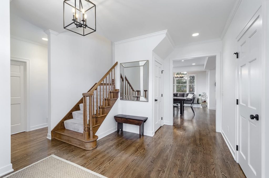 Bright foyer with wooden staircase and hardwood floors