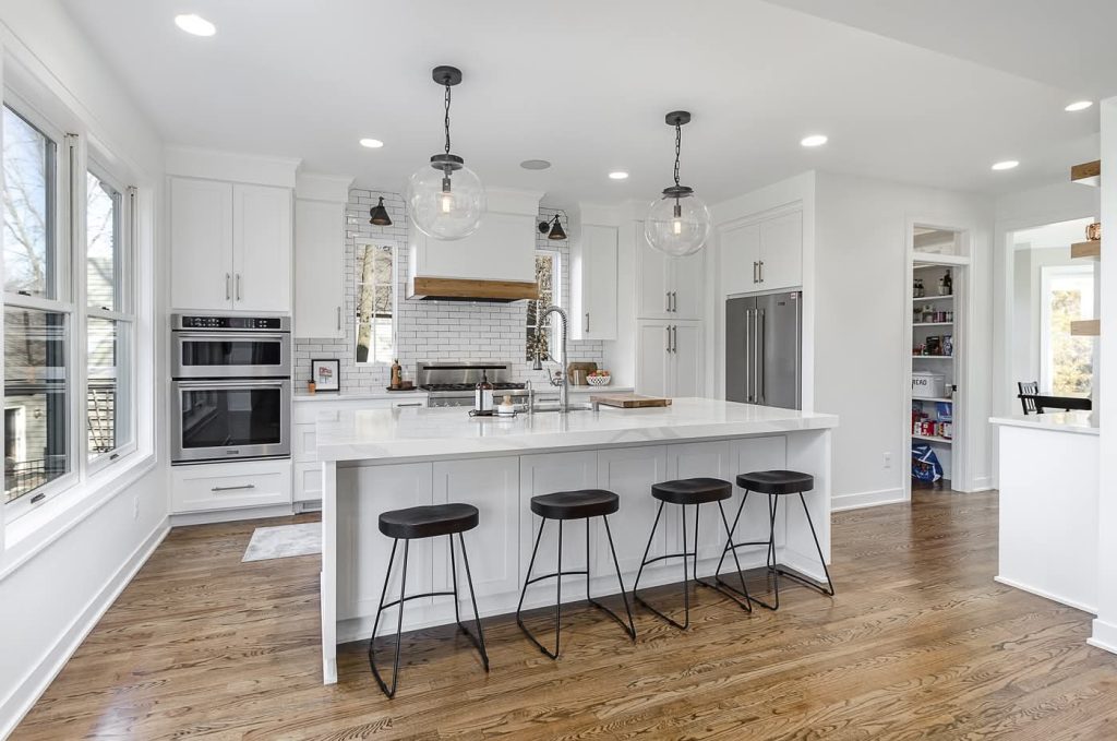 Modern white kitchen with island and black stools