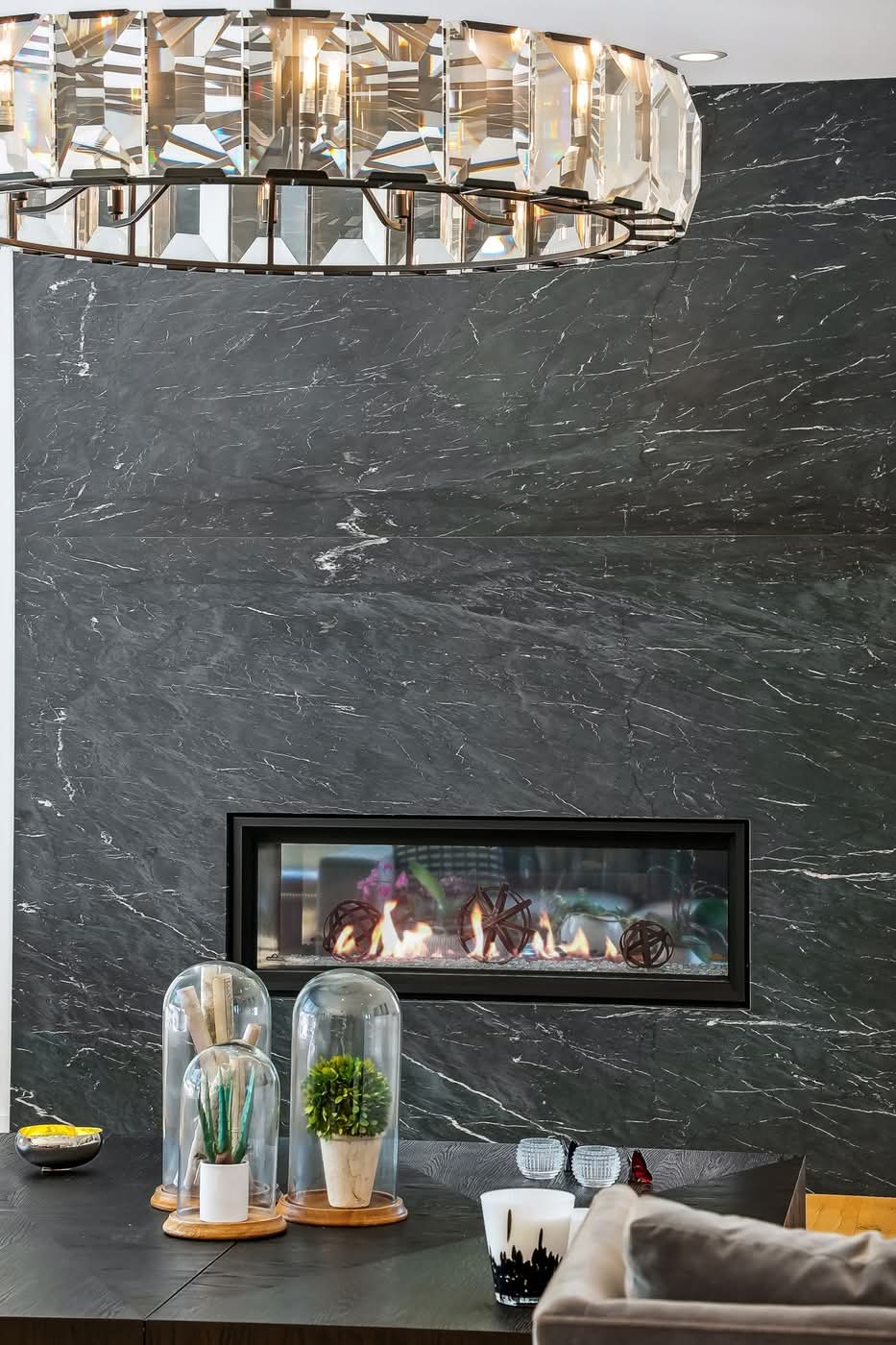 Modern black marble fireplace with contemporary chandelier above