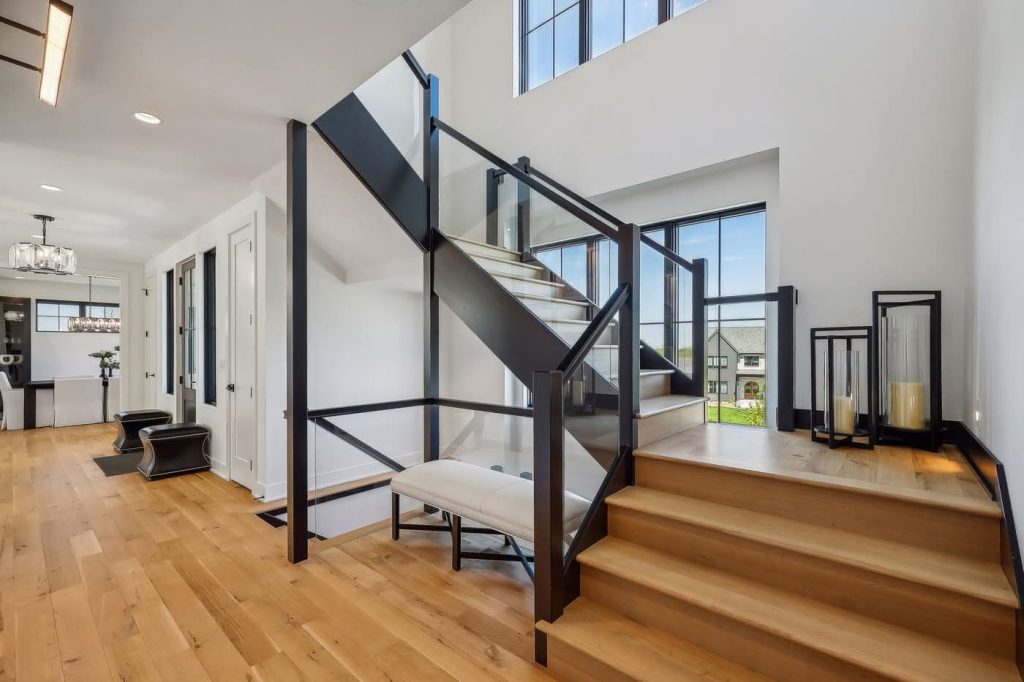 Modern staircase with glass railing and hardwood floors